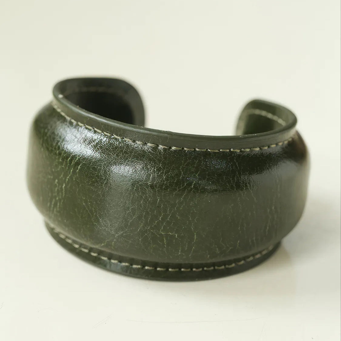Dark green leather cuff on a light beige background