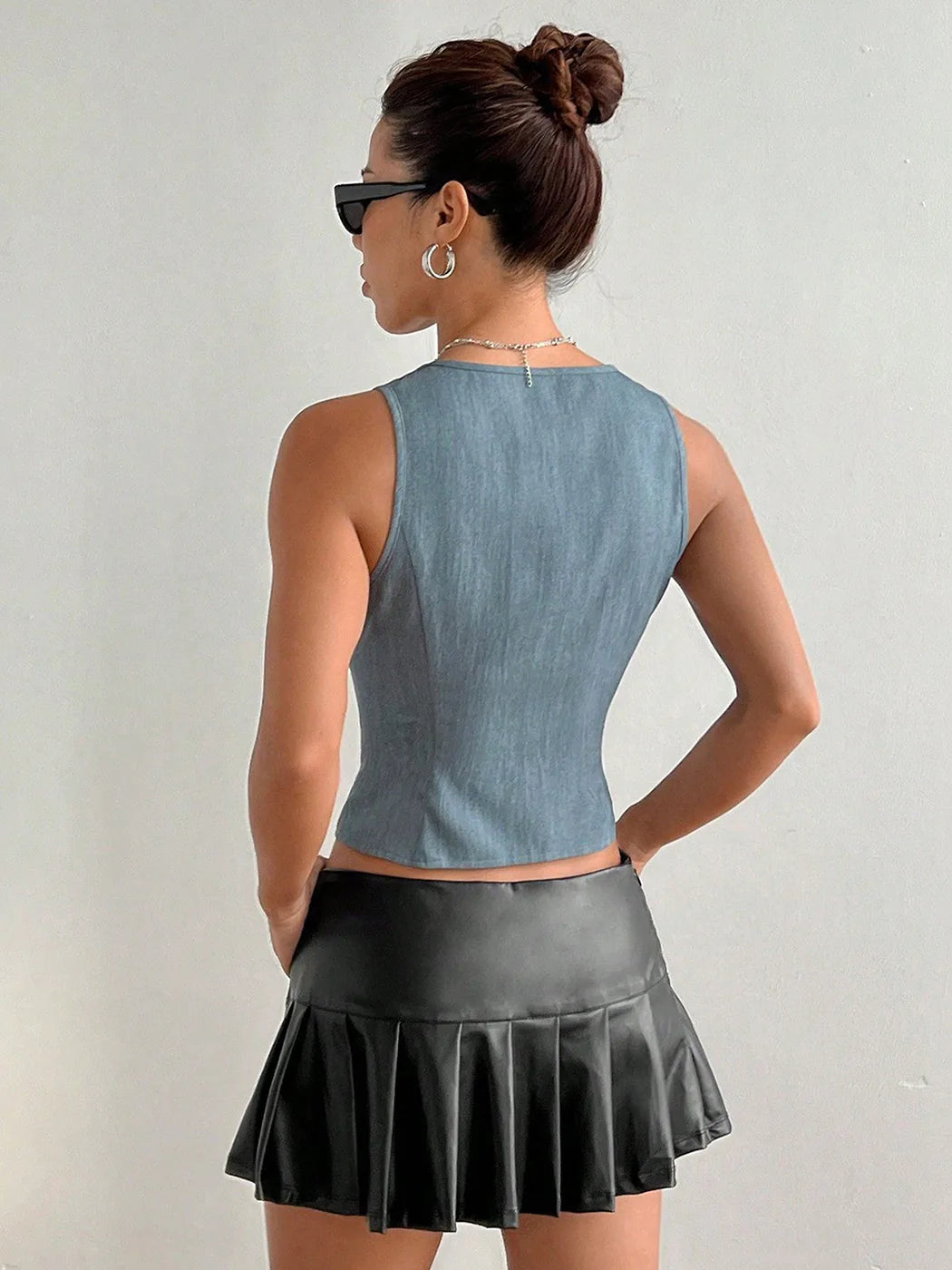 Woman wearing a denim top and black pleated skirt against a plain background #Color_LightGray