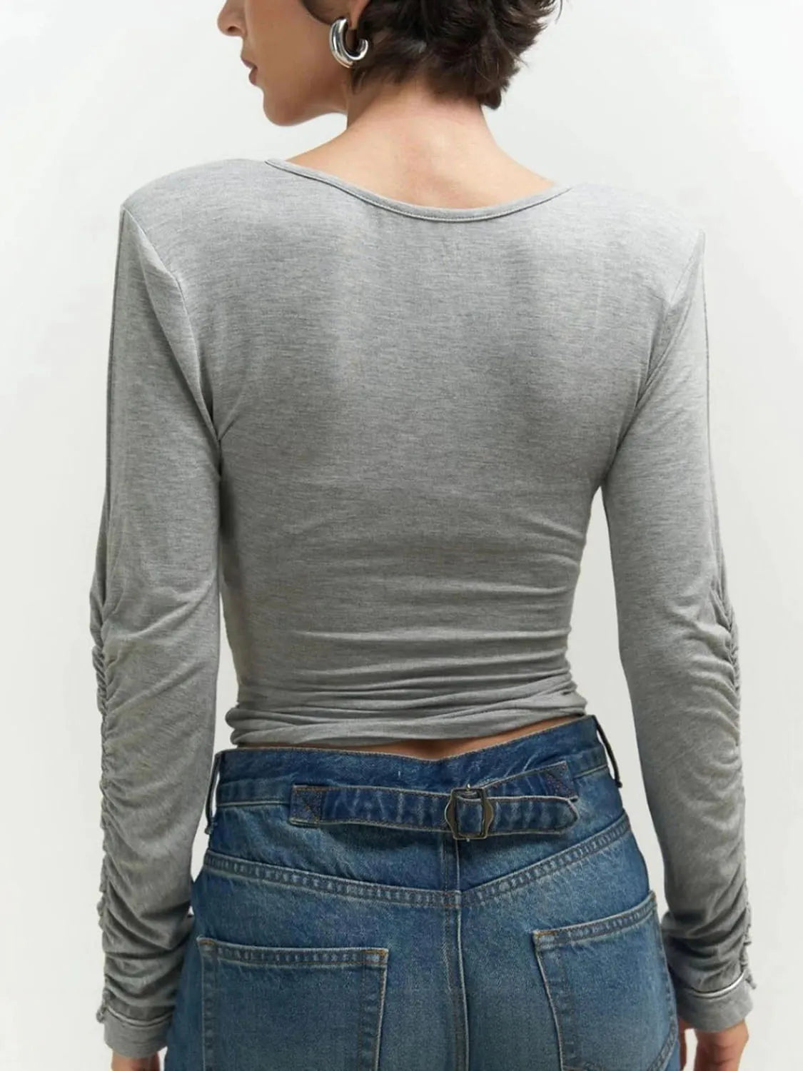 Person wearing a gray long-sleeve top and blue jeans on a white background. #Color_Gray