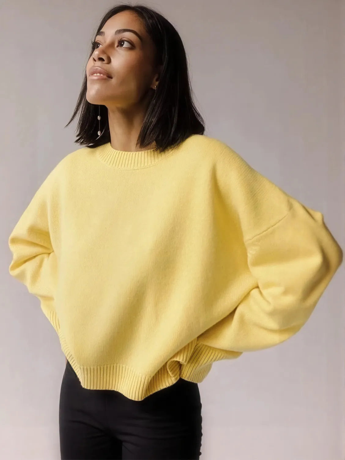 Woman wearing a yellow sweater against a plain background. #Color_Yellow