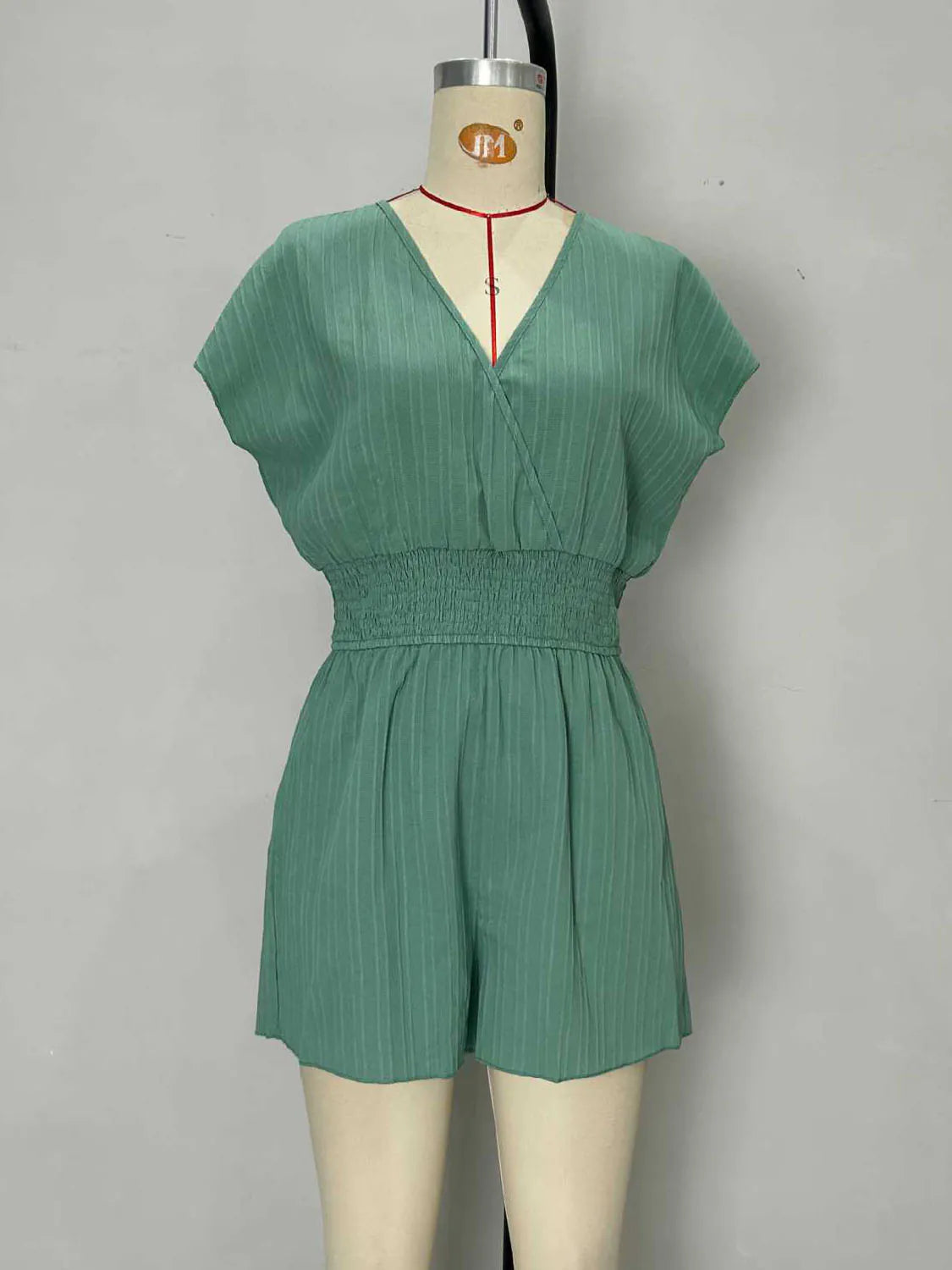 Green romper on a mannequin against a gray background. #Color_Green