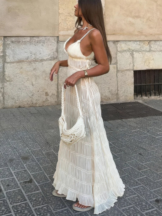 Woman in a long, light-colored dress standing on a street.