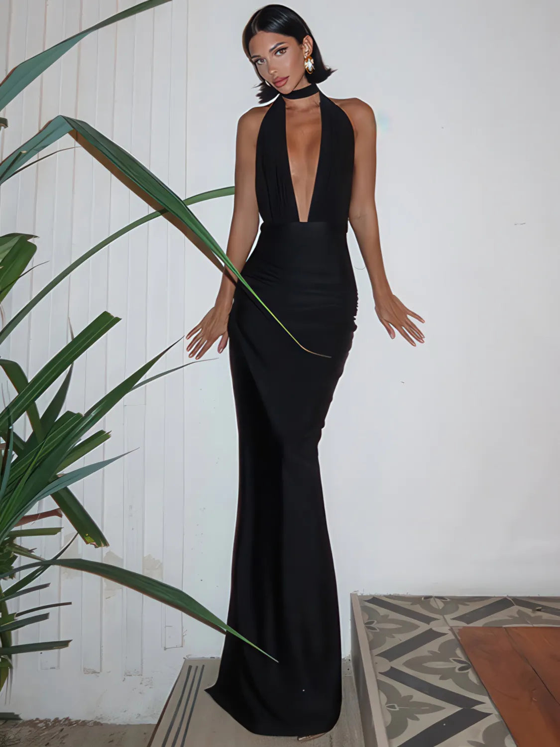 Woman in a black evening gown standing next to a plant indoors. #Color_Black
