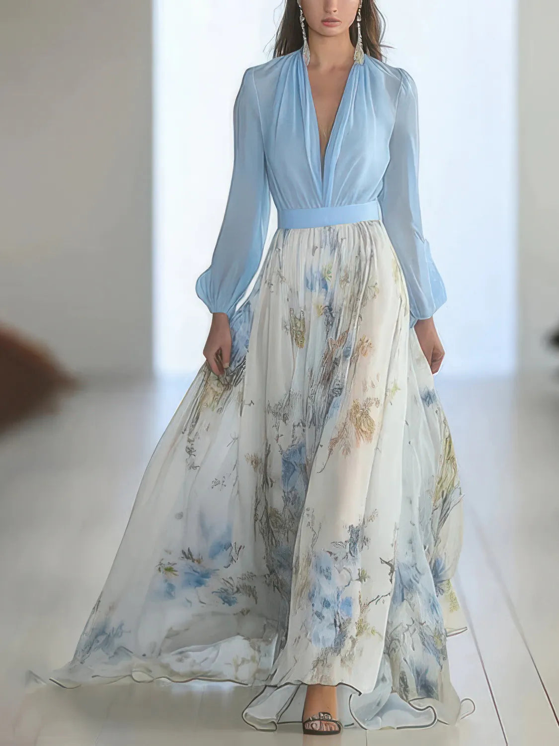 Woman wearing a light blue top and floral skirt in a minimal indoor setting