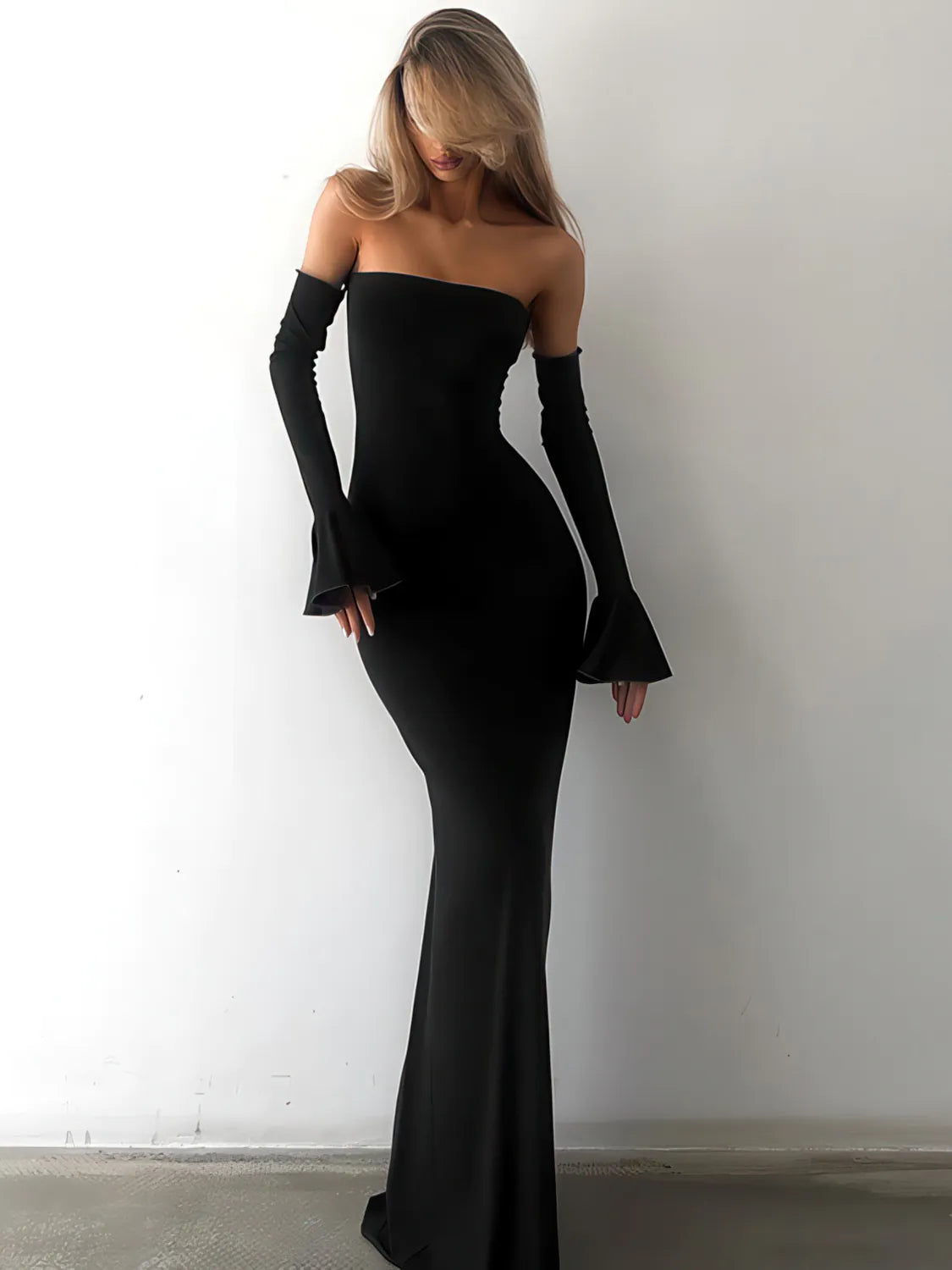 Woman wearing a black off-shoulder dress with long gloves against a white background. #Color_Black
