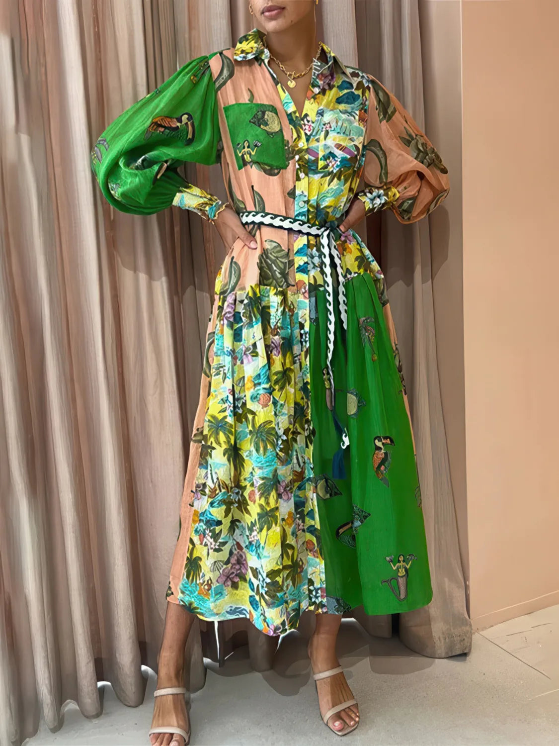 Woman wearing a colorful floral dress with green accents against a beige curtain background. #Color_RosyBrown