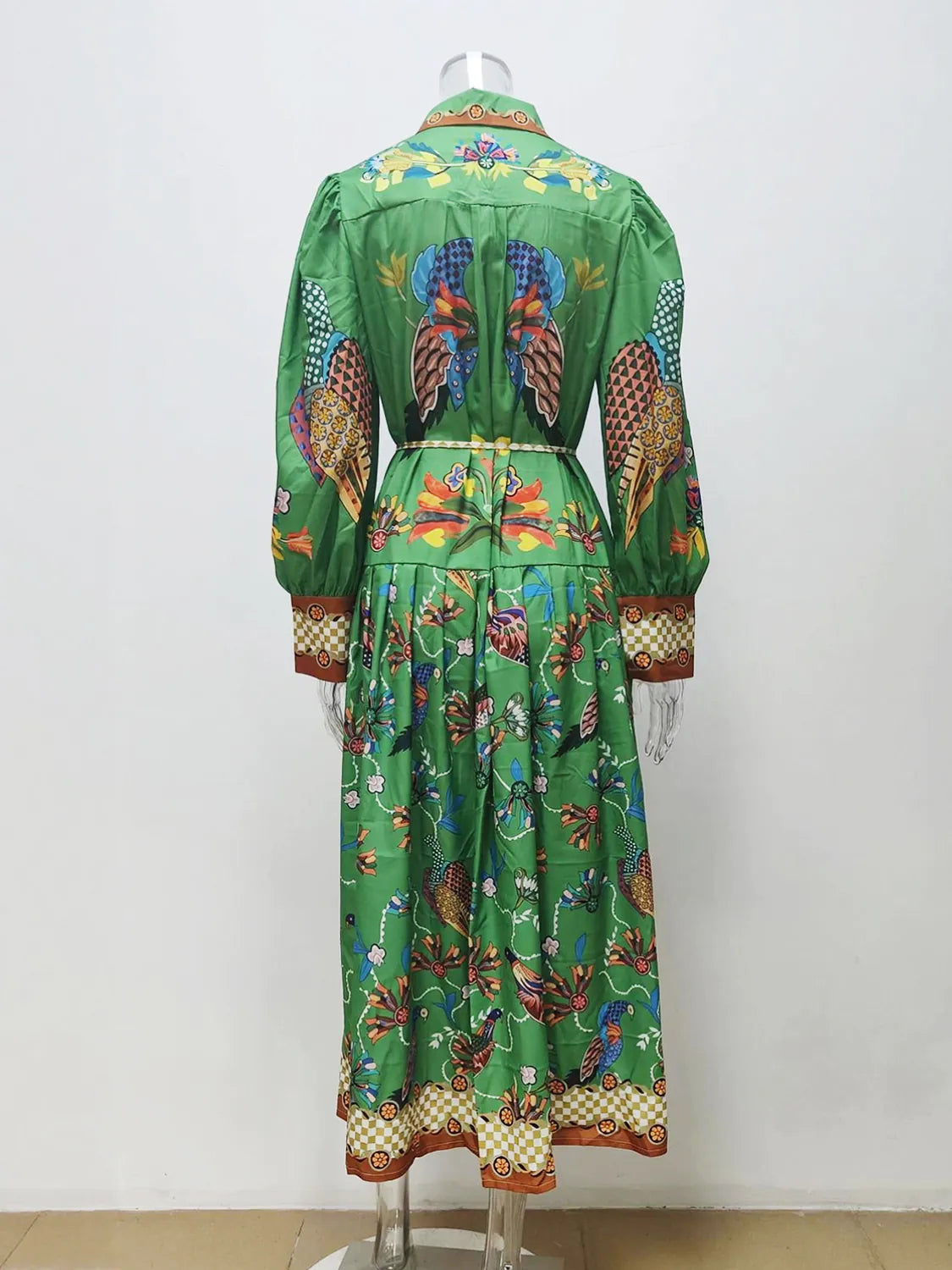 Green dress with colorful parrot pattern on a mannequin against a white background. #Color_Green